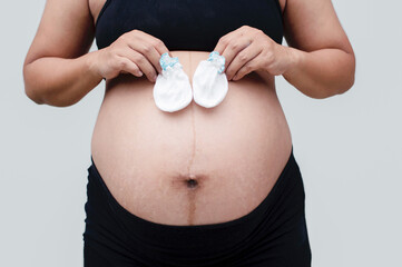 Close up of pregnant belly. Young beautiful pregnant woman standing on white background.