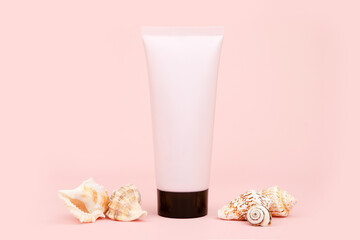 Unbranded pink squeeze bottle cream tube with black screw cap and a lot of different sea shells on...