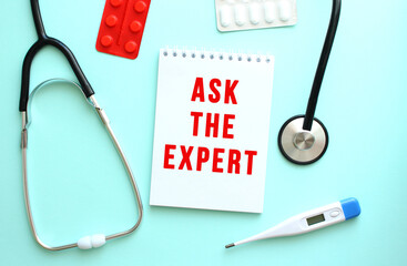 The red text ASK THE EXPERT is written on a white notepad that lies next to the stethoscope on a blue background.