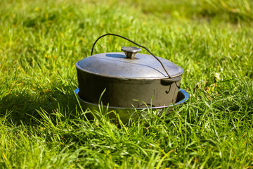 Camping gray aluminum cauldron stands on a green grass on a sunny summer day. Cooking in nature...