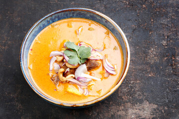Massaman curry in an oriental bowl, on a black stony background, top view. Thai curry based on...