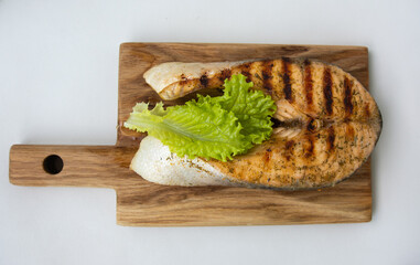 salmon with a few lettuce leaves on an oak board