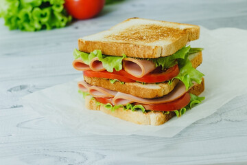 Sandwich with meat, salad, vegetables, lettuce, tomato on a rye bread on wooden background