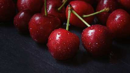 Cherry tree macro black background top view. Ripe juicy cherry berries in drops of water are lying on the table. The concept of freshness, proper nutrition, vitamins. Low key, close-up. Copy space