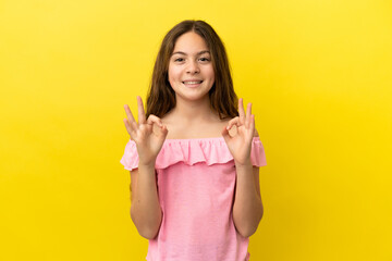Little caucasian girl isolated on yellow background showing ok sign with two hands