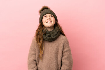 Little girl with winter hat isolated on pink background laughing