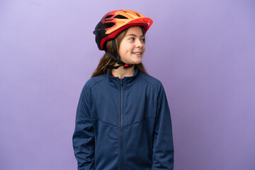 Little caucasian girl isolated on purple background looking to the side and smiling