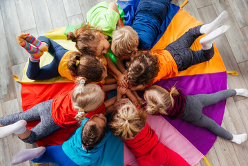 Cheerful children playing team building games on a floor - obrazy, fototapety, plakaty