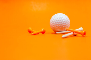 Golf ball and tee are on orange background