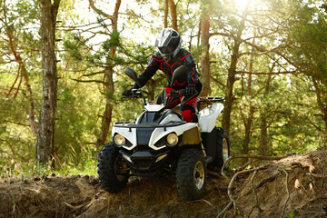 Man driving modern quad bike in forest. Extreme sport