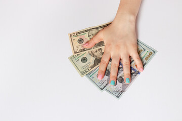 A woman's hand with multicolored manicure nails holds many dollar bills on a white with place for text copy space banner. Credit, corruption, borrowing money and financial literacy