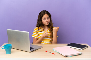 Little student girl in a workplace with a laptop isolated on purple background making the gesture of being late