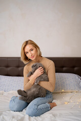 Pets, morning, comfort, rest and people concept - happy young woman with cat in bed at home