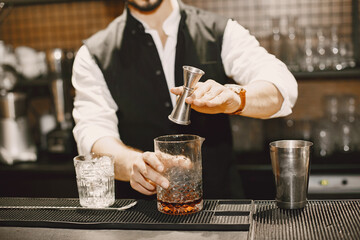 Bartender pours brown alcoholic drink to glass