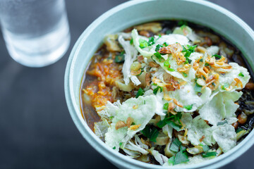 Close up on a bowl of chicken porridge in a bowl on a black background