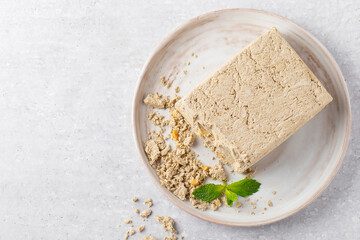 sunflower halva and peanuts on grey plate with mint, top view, grey background