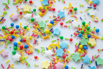 Obraz premium Multi-color festive background of a scattering of sugar candy sprinkles for cupcakes and other pastries in form of stars, sticks and balls. Pastel colors of red, pink and green, blue and yellow