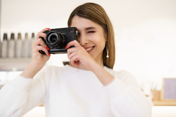 Naklejka premium Portrait of beautiful photographer woman working in office holding camera with laptop. Bloger freelance online marketing.