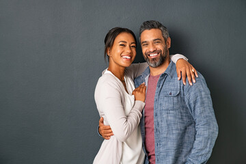 Mature multiethnic couple embracing and smiling together - obrazy, fototapety, plakaty