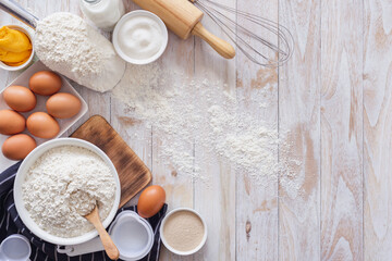 Homemade dough recipe (eggs, flour, milk, sugar) on a wooden table top view.