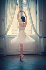 Portrait of beautiful ballerina near mirror. Image with selective focus, noise effect and toning
