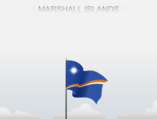 The Marshall Island flag flutters on a pole that stands tall against a white sky