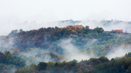 Fog and clouds rising from an autumn forest