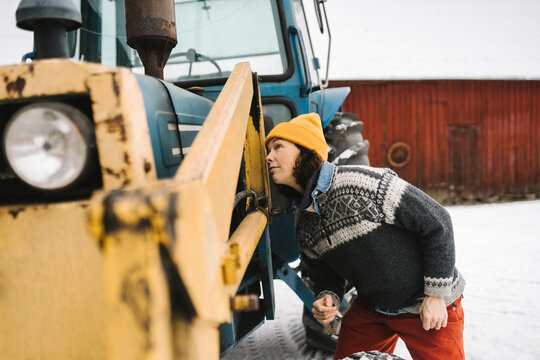 Fundersam kvinna tittar p&aring; traktor st&aring;ende utomhus