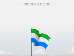 Sierra Leone flag flutters on a pole standing tall under a white sky