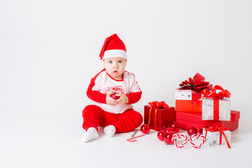 baby boy in santa hat with gifts on white background
