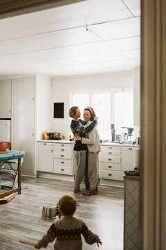 K&auml;rleksfullt par st&aring;r och tittar p&aring; dotter som leker i k&ouml;k