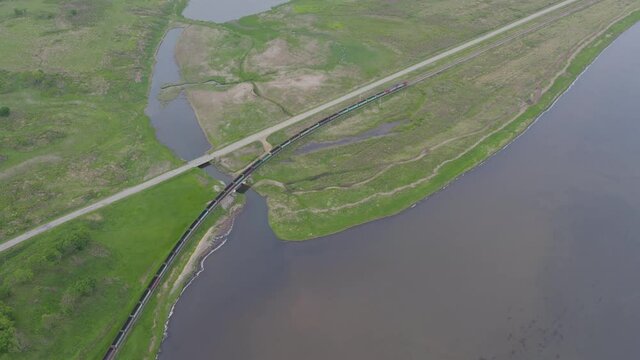 A drone view of a freight train driven by a diesel locomotive on a railroad