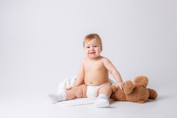 baby boy in a diaper sits on a white background with a teddy bear