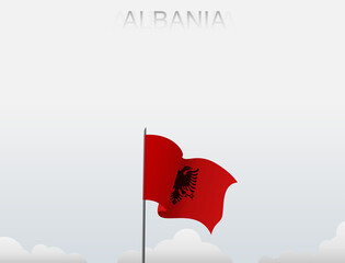 Albania flag flutters on a pole standing tall under a white sky