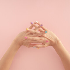 women hands with colorful nails on the pastel pink background. copy space.  summer modern tropical abstract art with female hand. minimal background idea with copy space