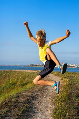 Fototapeta premium Boy jumping on cliff, running outdoor. Having fun, Summer vacation holiday lifestyle. Freedom and success concept. Dynamic and emotional scene
