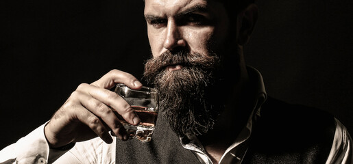 Attractive man with a whiskey. man with stylish hair mustache and beard drinking brandy or whiskey from glass