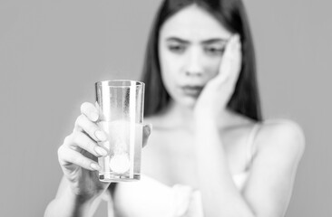 Young woman taking pill against headache. Brunette taking a pill with a glass of water. Black and white