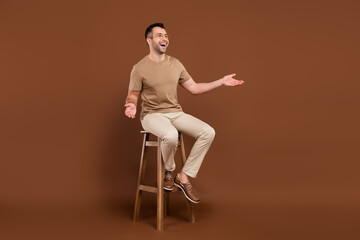 Photo of pretty impressed gentleman wear beige t-shirt spectacles sitting chair looking empty space...