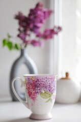 Composition of beautiful cup of tea with lilac flowers on background