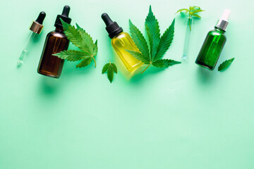 Cannabis oil in bottle hemp oil and cannabis leaves at green background. Top view, copy space.