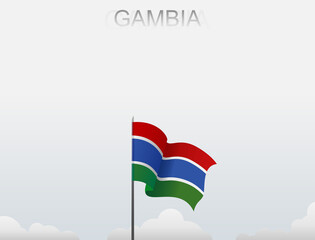 Gambia flag flutters on a pole standing tall under a white sky