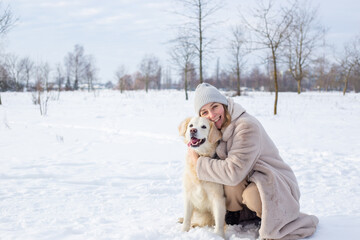 Young beautiful woman and her golden retriever dog having fun in winter.