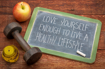 love yourself enough to live a healthy lifestyle - inspirational handwriting in white chalk on a slate blackboard with a dumbbell, apple and tape measure