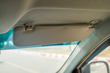 Car visor. Car interior. Grey open sun car visor with selective focus and car mirror on blurred background with automobile window