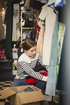 Kvinna sitter p&aring; huk och packar upp paket i butik