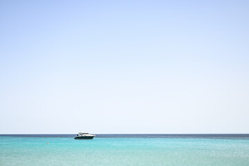 Small luxury blue speedboat at anchor in tranquil turquoise sea waters