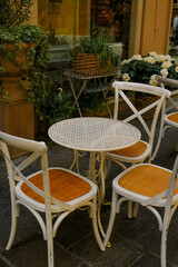 White wooden table with chairs across plants in pots in restaurant terrace. Cafe exterior. City life	
