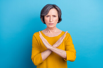 Portrait of attractive serious woman showing crossed hands ban sign isolated over vivid blue color...