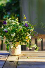 Bouquet of field flowers on a garden table lit by rays of sun 
